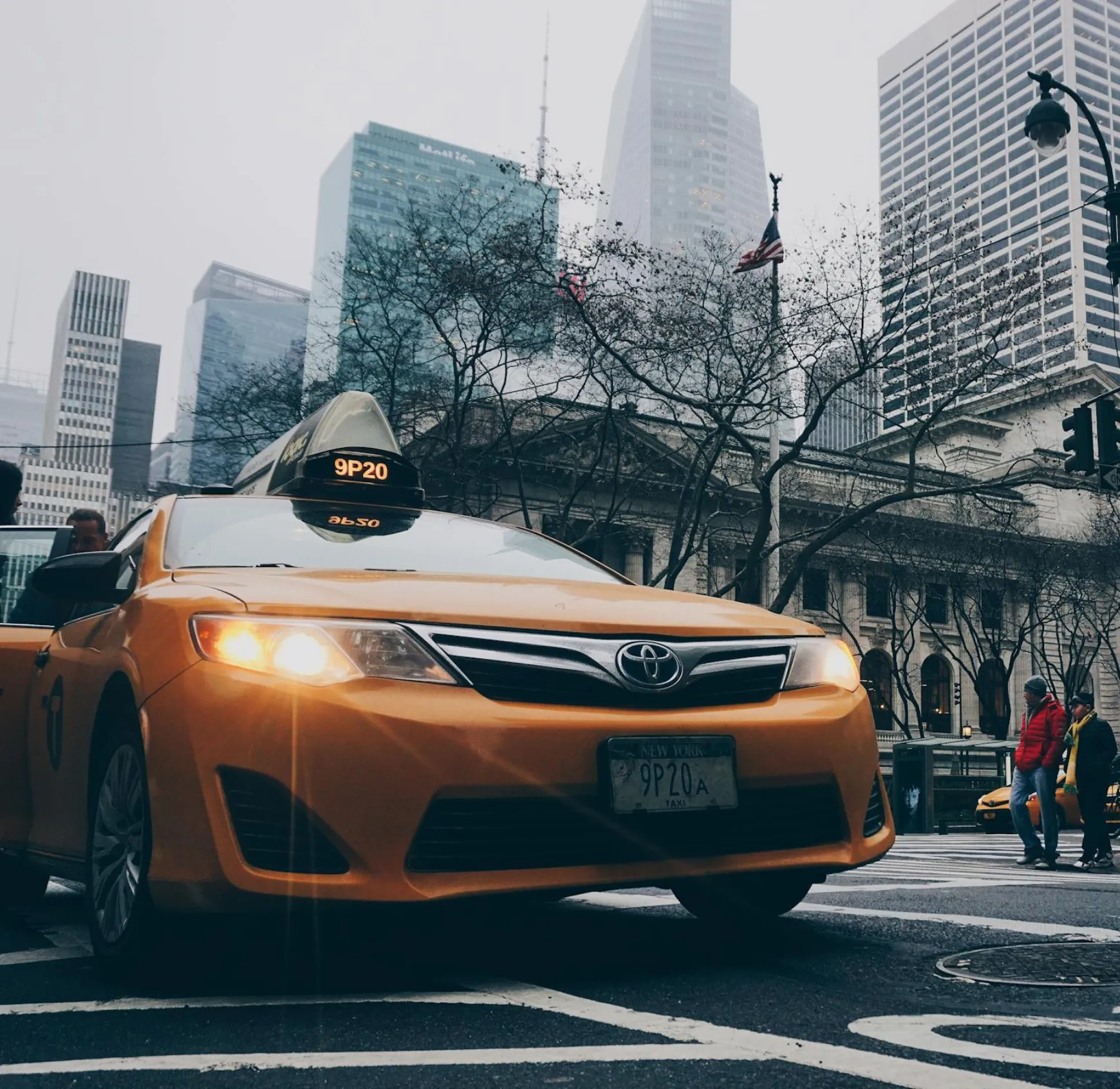 A taxi cab driving down a street next to tall buildings.